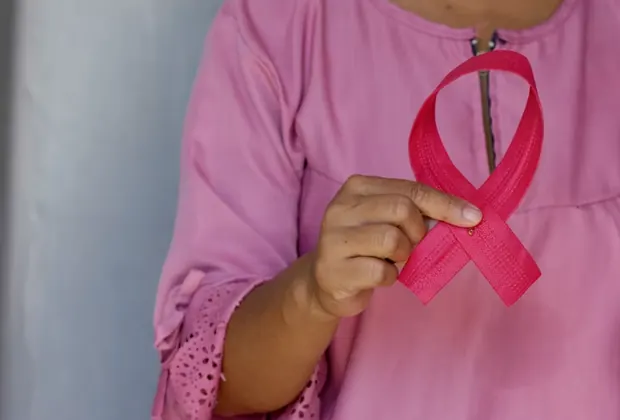 Pessoa segurando laço rosa do combate ao câncer de mama